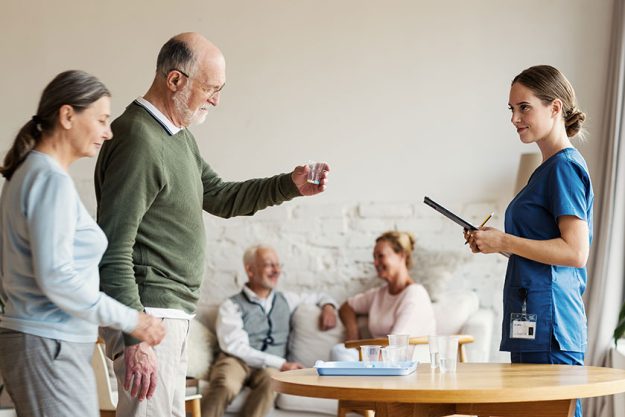 Elderly man and woman taking plastic glasses with vitamin pills