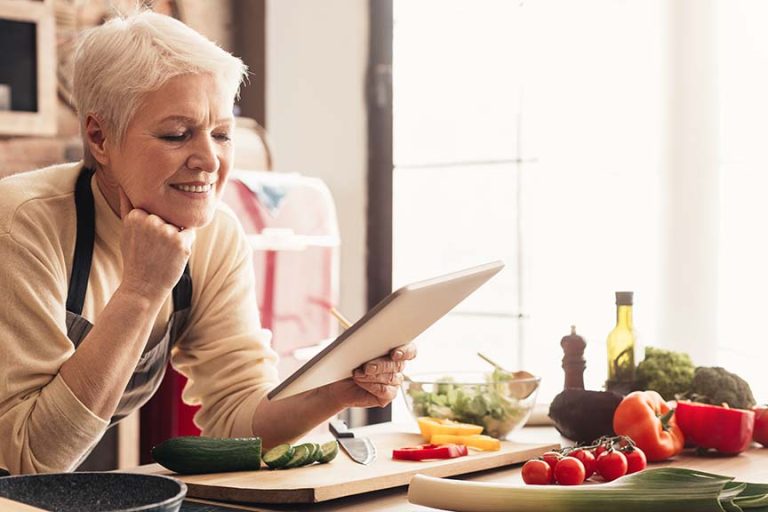 woman using digital tablet at kitchen A Guide To Preparing Healthy Meals For Seniors