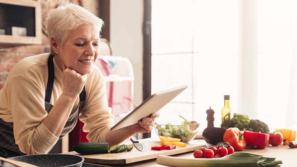 woman using digital tablet at kitchen A Guide To Preparing Healthy Meals For Seniors