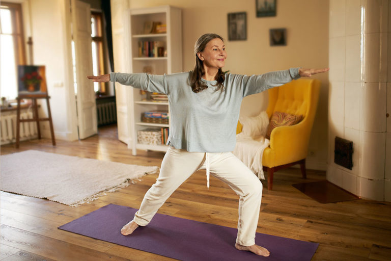 Full length shot of happy energetic mature woman in casual clothes exercising at home because of social distancing