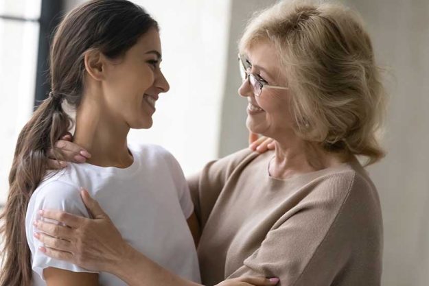 Smiling elderly mother and adult daughter look in eyes Smiling elderly mother and adult daughter look in eyes