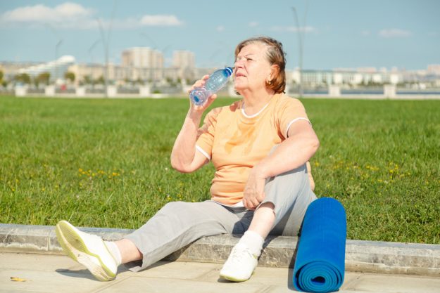 Pensioner woman resting after training in the park. Fitness trai