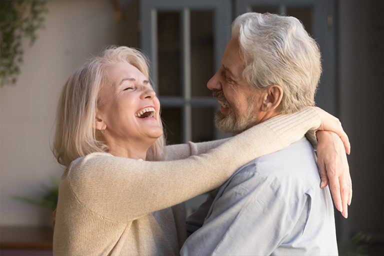 happy elderly spouses embracing standing indoors happy elderly spouses embracing standing indoors