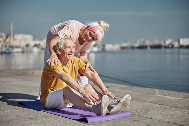 Joyful elderly man doing a stretching exercise