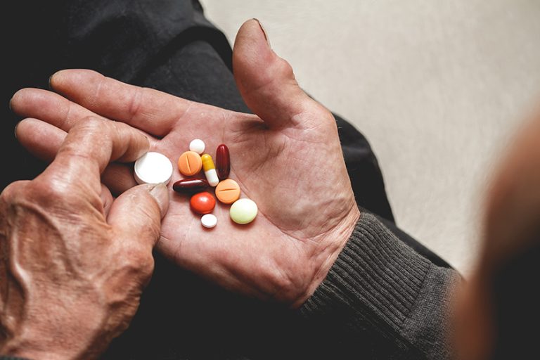 Many multi-colored pills in a Senior’s hands. Many multi-colored pills in a Senior's hands.