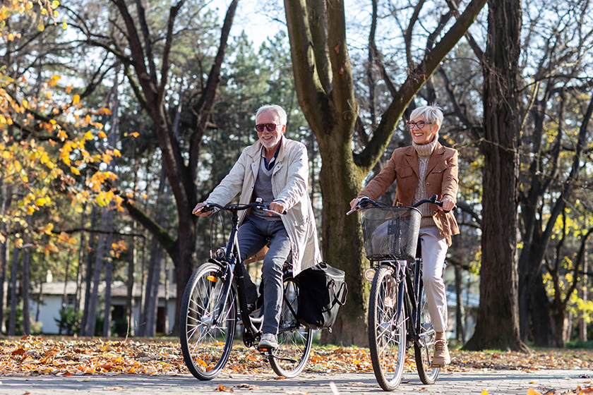 Mature fit couple ride in bicycles thru public park Mature fit couple ride in bicycles thru public park