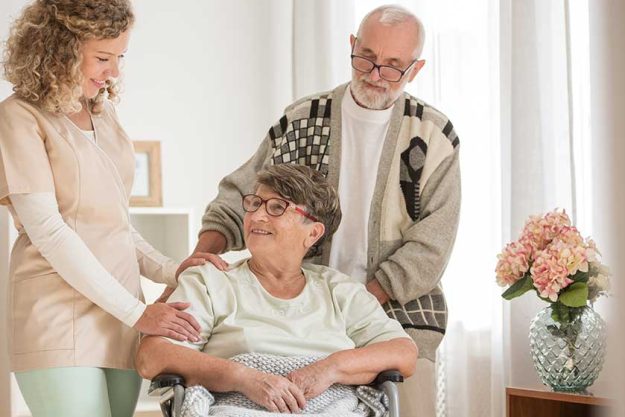 Elderly couple with their helpful caregiver in nursing home