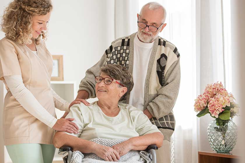 Elderly couple with their helpful caregiver in nursing home