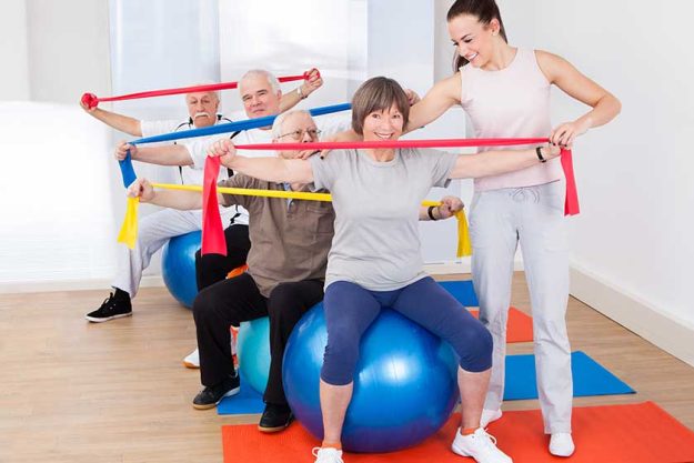 Trainer Assisting Senior People At Gym