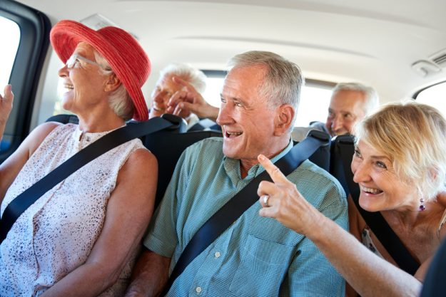 Group Of Senior Friends Sitting In Back Of Van Being Driven To Vacation Group Of Senior Friends Sitting In Back Of Van Being Driven To Vacation