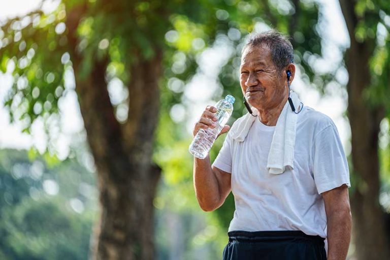 Happy thirsty senior man drinking fresh water after sports in park Happy thirsty senior man drinking fresh water after sports in park