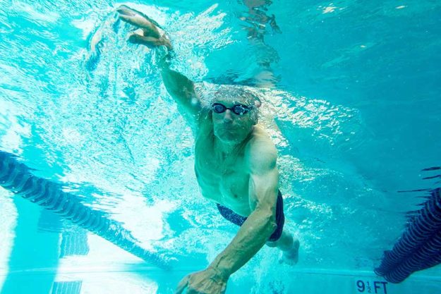 senior man swimming laps, underwater view