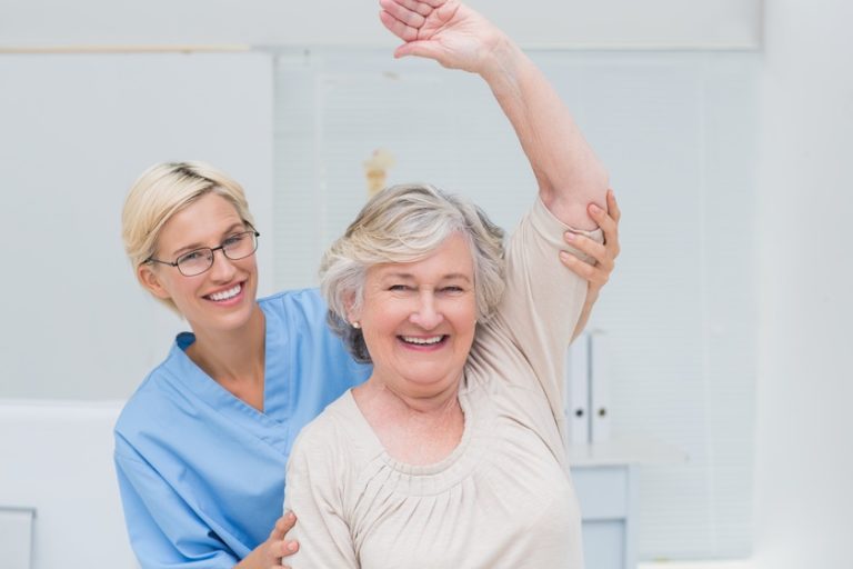 Senior patient being assisted by nurse in raising arm Senior patient being assisted by nurse in raising arm