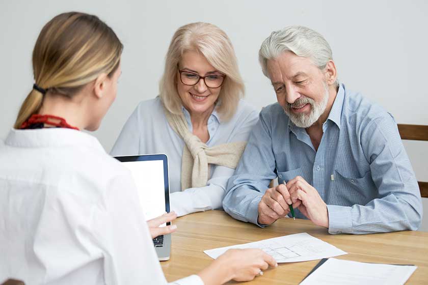 Real estate agent showing house plan to aged couple Real estate agent showing house plan to aged couple