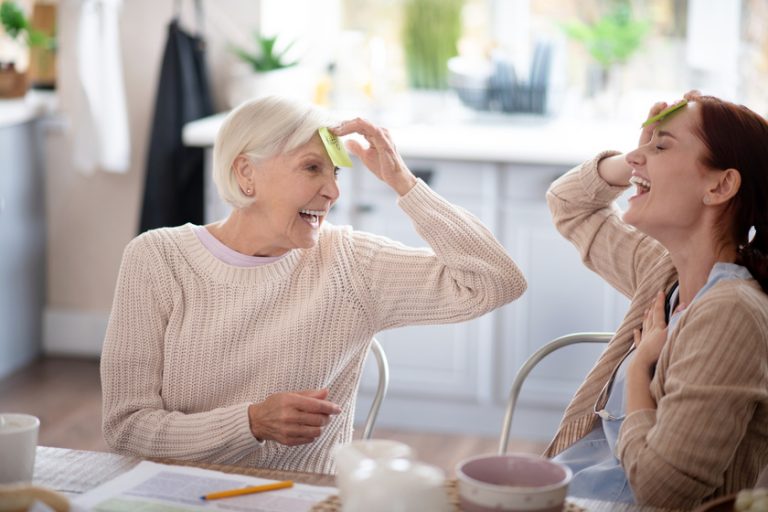 Laughing pensioner playing words game with nurse What Makes An Effective Dementia Care? 3 Fundamentals