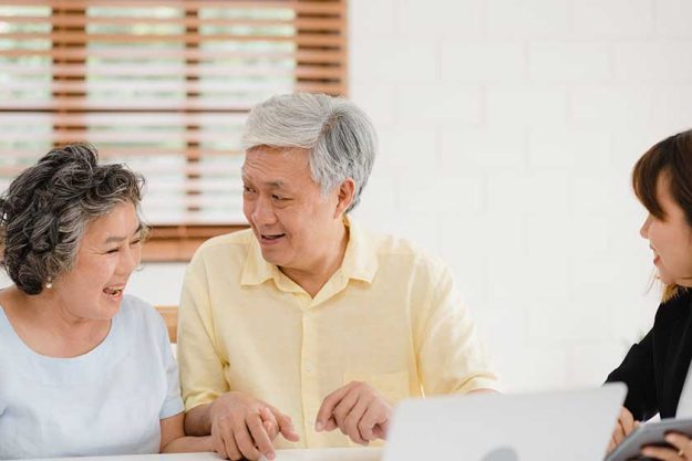 Asia smart female agent offers health insurance for elderly couples by document, tablet and laptop