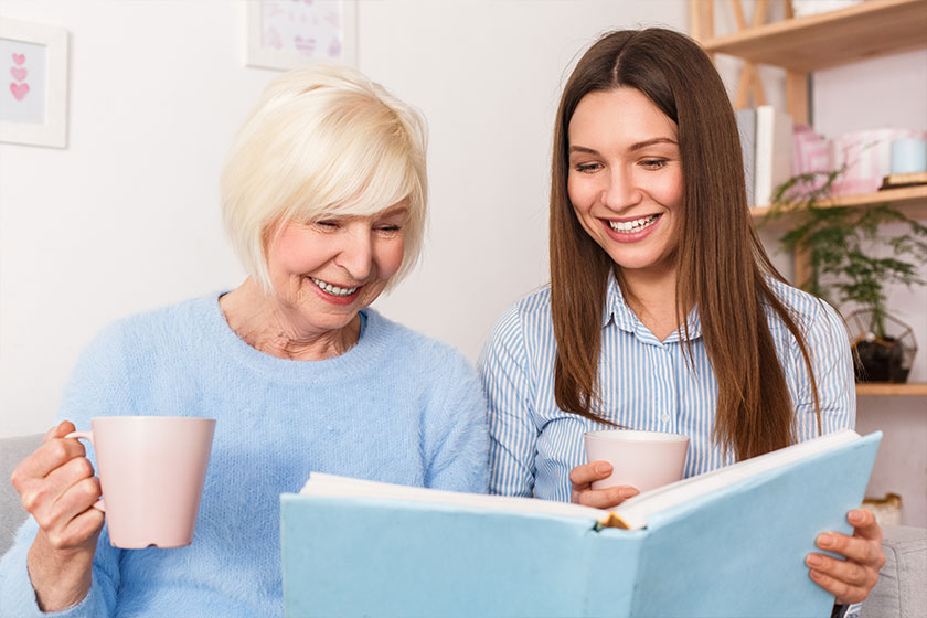 Grandmother and granddaughter watching old family album and laughing