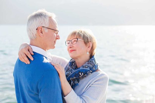 Happy senior couple at sea beach outdoor. Man and woman are hugging