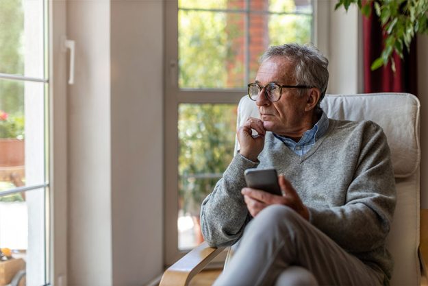 Senior man using mobile phone at home