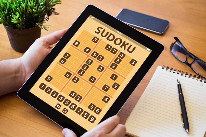 Man holding tablet with sudoku
