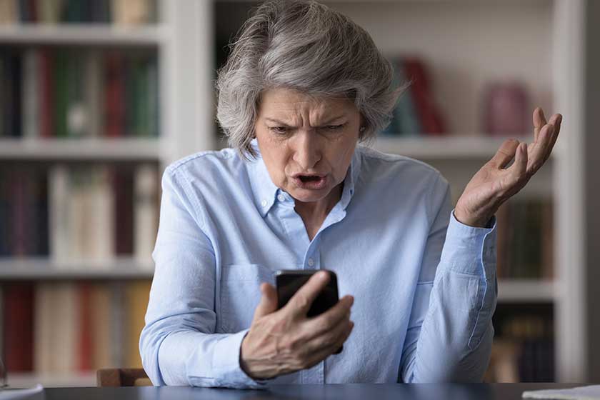 Angry older businesswoman sit at workplace