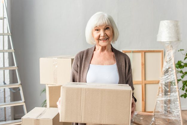 Cheerful senior woman holding cardboard box Cheerful senior woman holding cardboard box