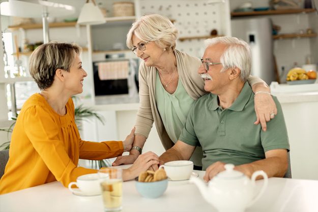 Happy Woman Visiting Her Senior Parents Communicating Them Home