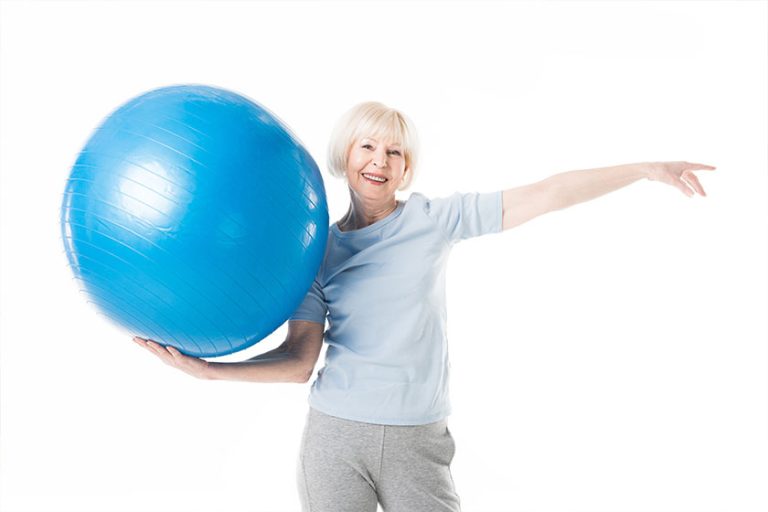 Smiling senior sportswoman holding fitness ball Smiling senior sportswoman holding fitness ball