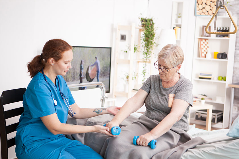 Caring physiotherapist helping old woman to exercise Caring physiotherapist helping old woman to exercise