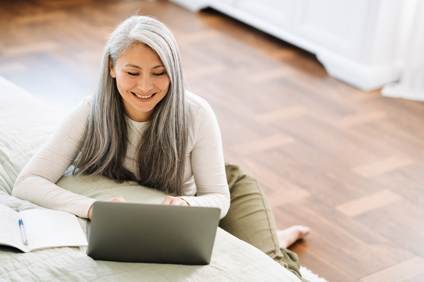 Mature asian woman with grey hair working with laptop in bedroom The Memory Care Facility Costs In Bonita Springs, FL