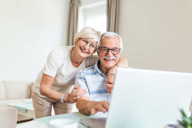 Elderly spouses at home. Wife hugs husband