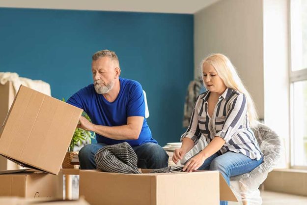 Mature couple unpacking moving boxes at new home