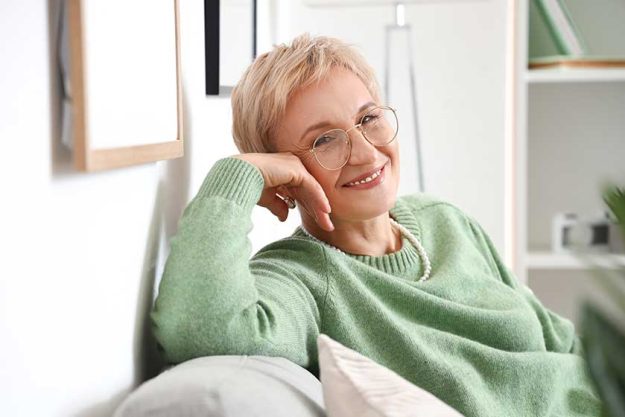 Mature woman sitting on sofa at home Mature woman sitting on sofa at home