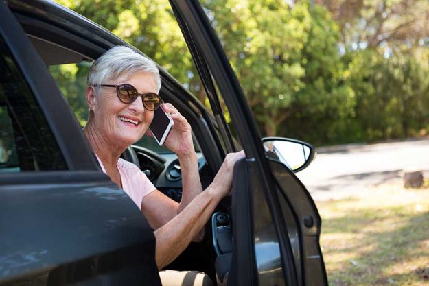 Senior woman talking on phone in car