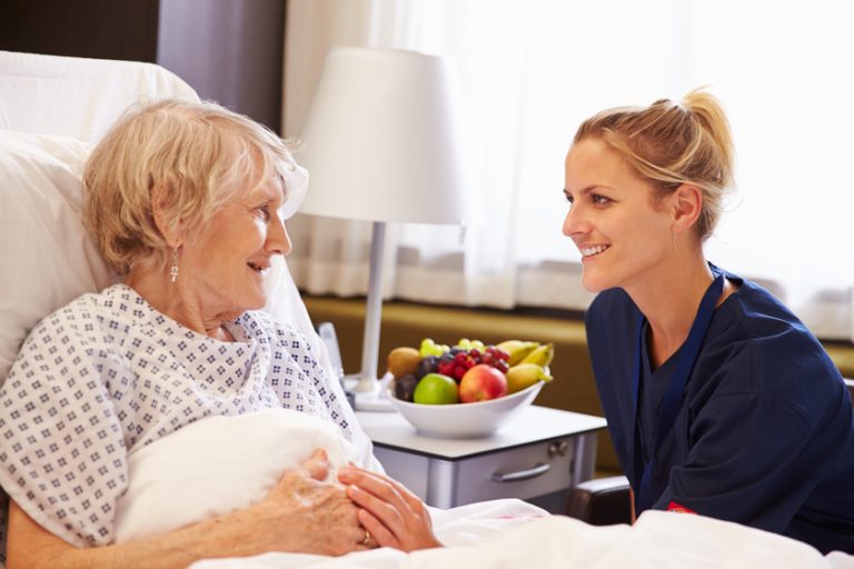 Nurse Talking To Senior Female Patient In Hospital Bed Nurse Talking To Senior Female Patient In Hospital Bed