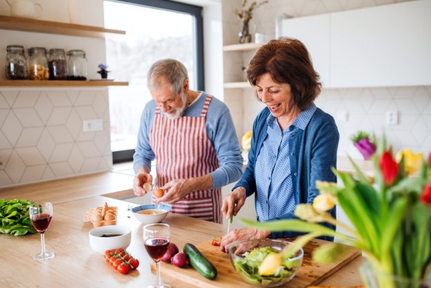 A portrait of senior couple in love indoors at home, cooking. A portrait of senior couple in love indoors at home, cooking.