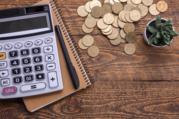 Calculator keypad,gold coins, pen and notebook