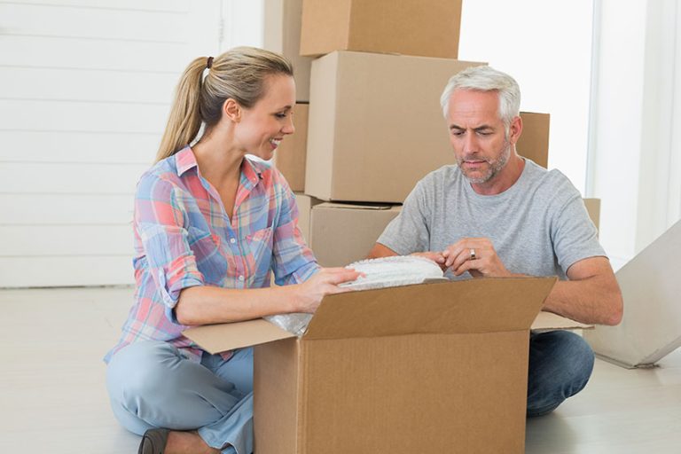 Happy couple unpacking cardboard moving boxes