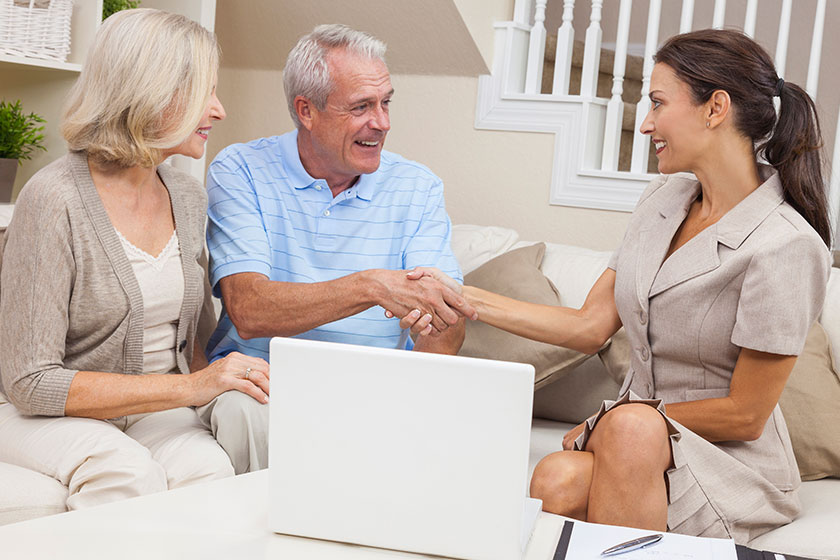 Saleswoman Shaking Hands With Senior Couple