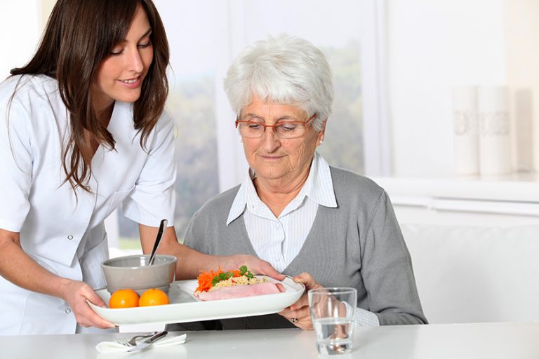 Beautiful nurse bringing meal tray