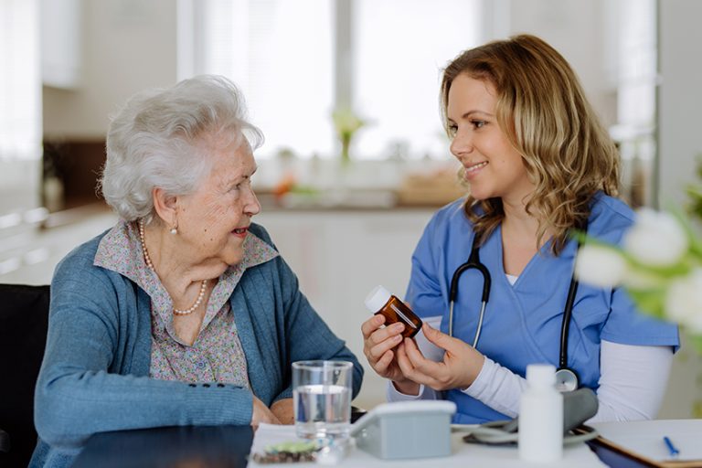 Nurse giving pills to senior woman in her home
