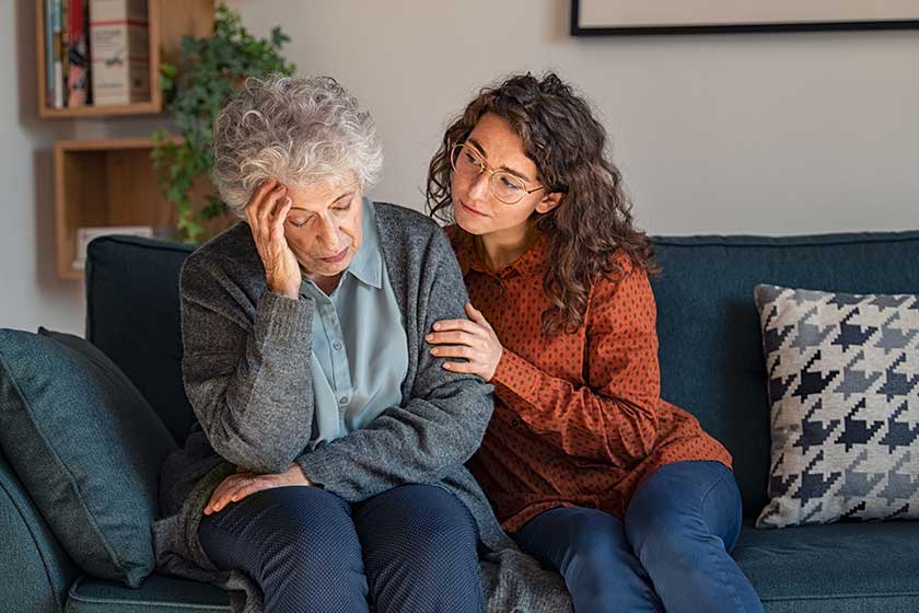Caring daughter comforting frustrated unhappy senior woman. Loving adult granddaughter talking to sad depressed old grandmother holding hand and comforting her. Upset widowed woman with headache consoled by her daughter.