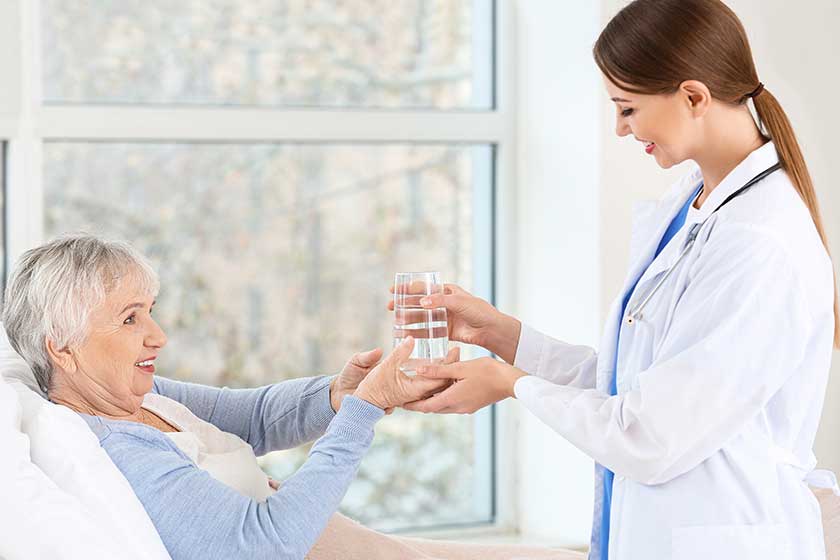 Female doctor giving senior woman suffering from Parkinson syndrome glass of water in clinic Female doctor giving senior woman suffering from Parkinson syndrome glass of water in clinic