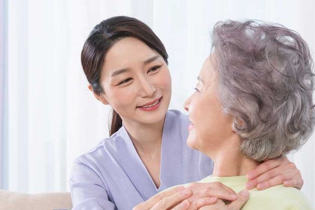 Happy smiling Asian old mother and middle aged daughter on sofa Happy smiling Asian old mother and middle aged daughter on sofa