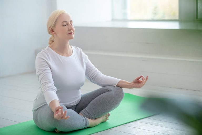 Mature blonde female sitting in lotus pose meditating Mature blonde female sitting in lotus pose meditating