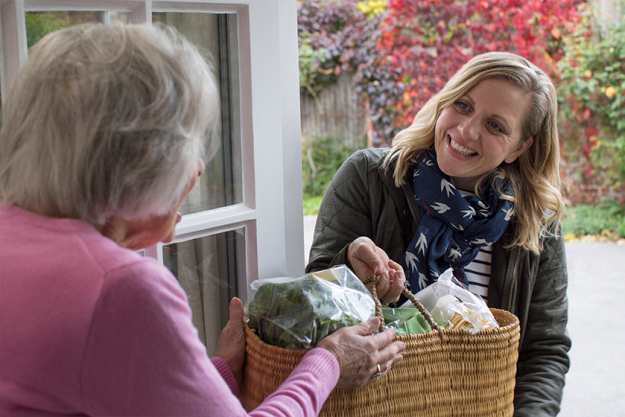 Female Neighbor Helping Senior Woman With Shopping Female Neighbor Helping Senior Woman With Shopping