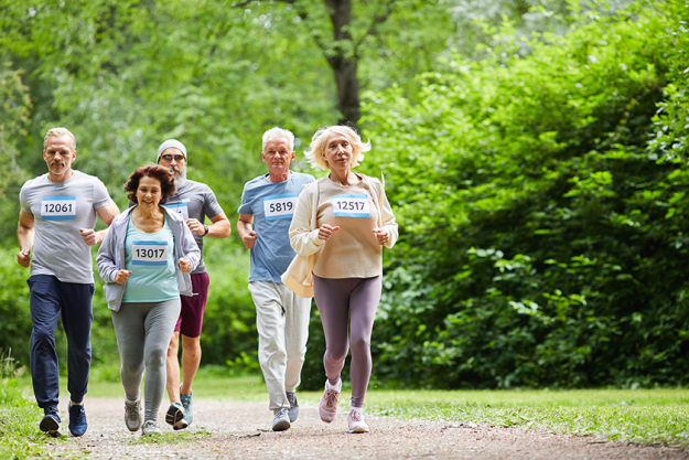Group of sporty senior men and women taking part marathon running forest