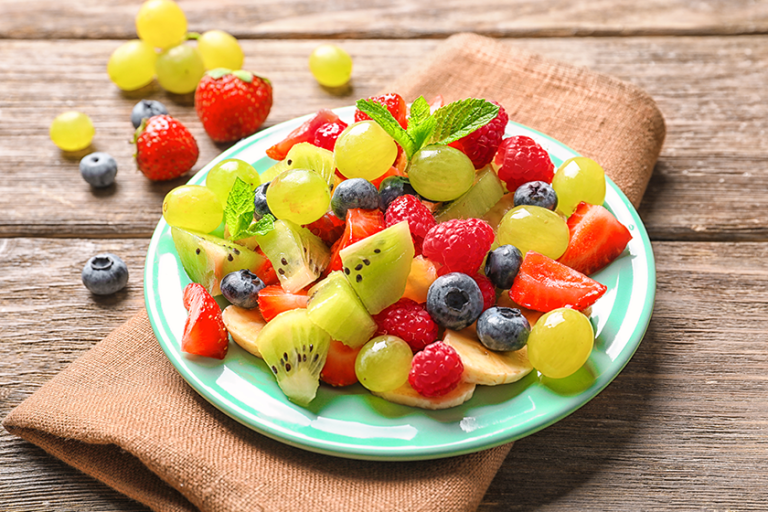 Plate with fruit salad on wooden table Plate with fruit salad on wooden table