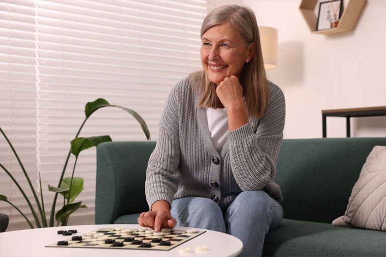 Happy senior woman playing checkers
