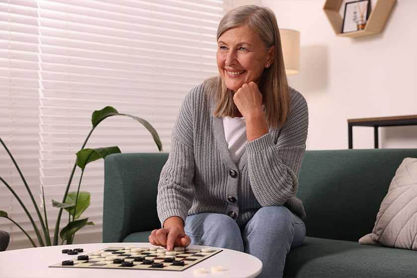 Happy senior woman playing checkers